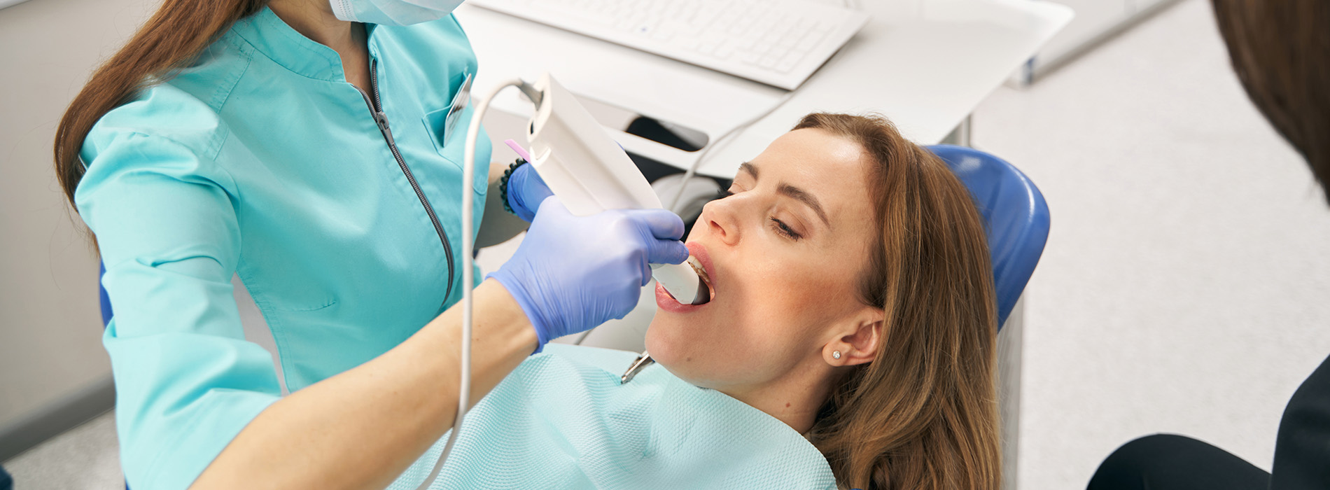 A dental hygienist is cleaning a patient s teeth using an ultrasonic scaler.