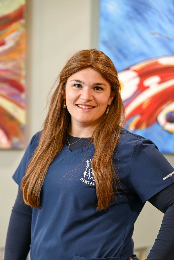 A woman in a blue uniform stands confidently with her hands on her hips.