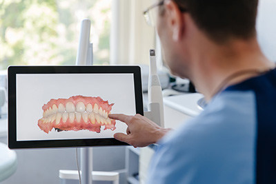 A dental professional using a digital display to showcase an oral health model, likely for educational or diagnostic purposes.