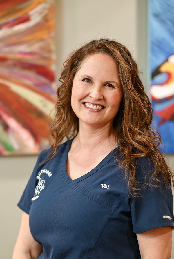 A woman in a blue scrub top, smiling and posing for the photo.