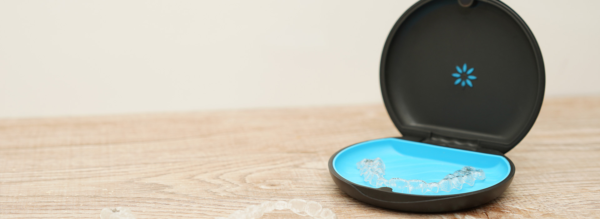 A small black smart home device with a blue circular light on top, placed against a white background.