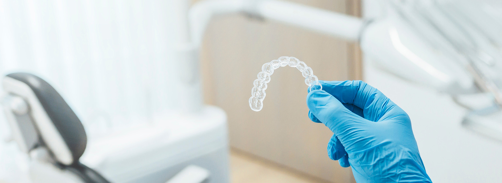 A close-up of a dental professional holding a transparent dental impression tray.