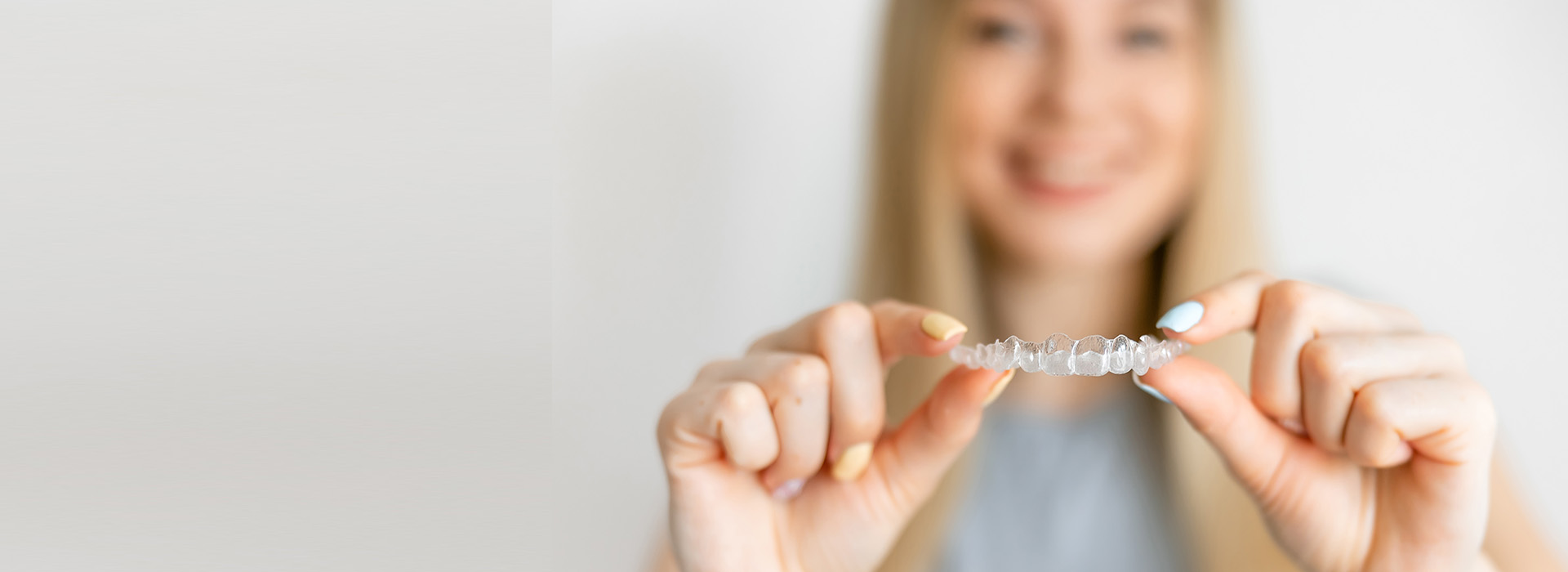 A person is holding a small, clear object with their left hand against a plain background.