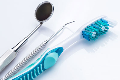 An image featuring dental tools, including a toothbrush and scissors, on a white background.