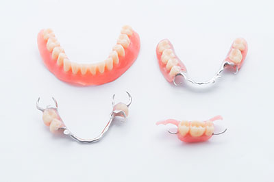 The image displays a set of upper and lower dentures with teeth missing, placed on a white surface.