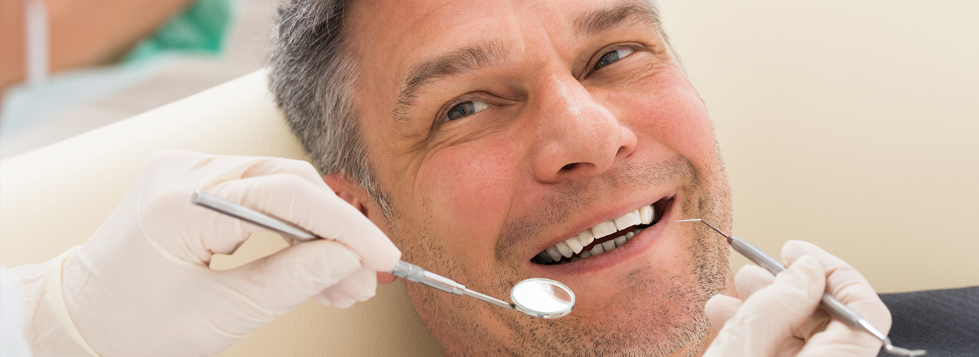 A man is seated in a dental chair, receiving dental treatment from a dentist.