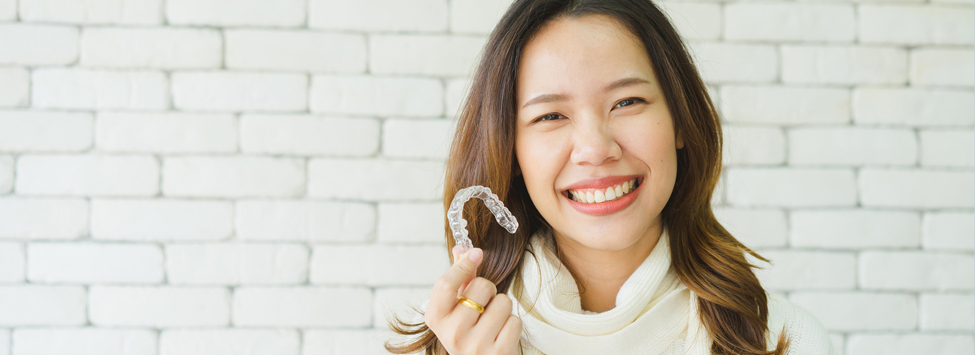 A woman wearing a ring is smiling at the camera.