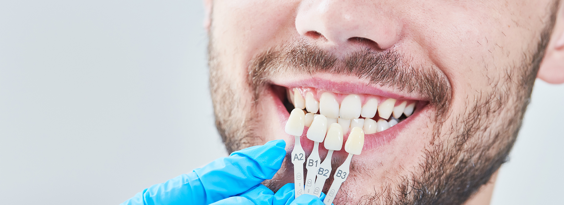 A man in a dental chair receives a teeth cleaning treatment, with dental instruments visible.